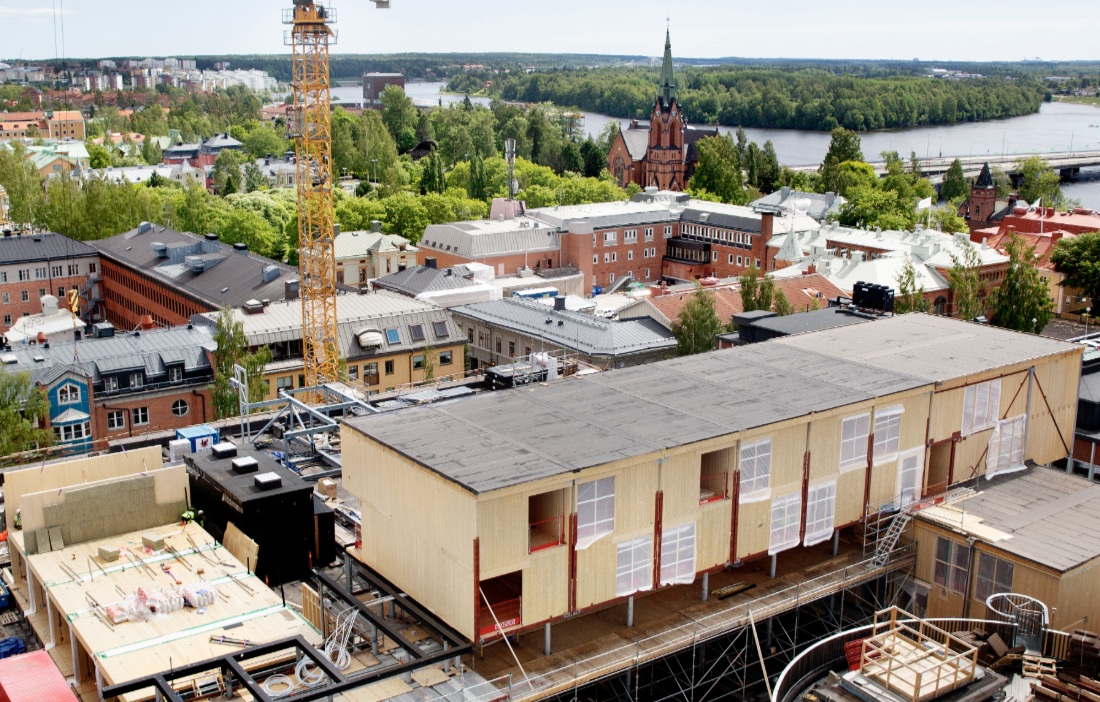 byggarbetsplats med byggande i trä med stor lyftkran.